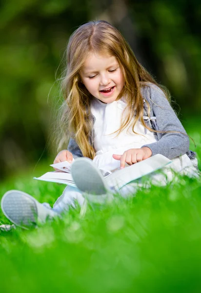 Zittend op het gras meisje leest boek — Stockfoto