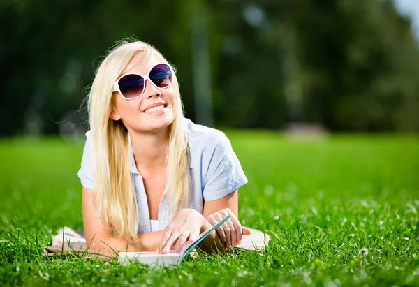 Studentin mit Sonnenbrille und Buch im Gras — Stockfoto
