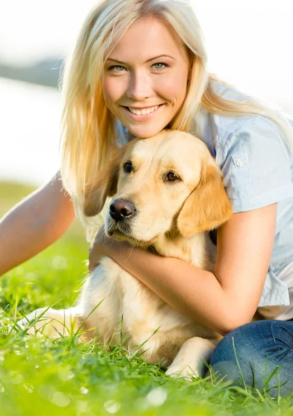 Woman embraces golden retriever on the grass — Stock Photo, Image