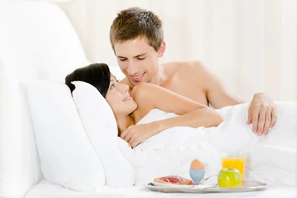 Homem serve café da manhã mulher no quarto de cama — Fotografia de Stock