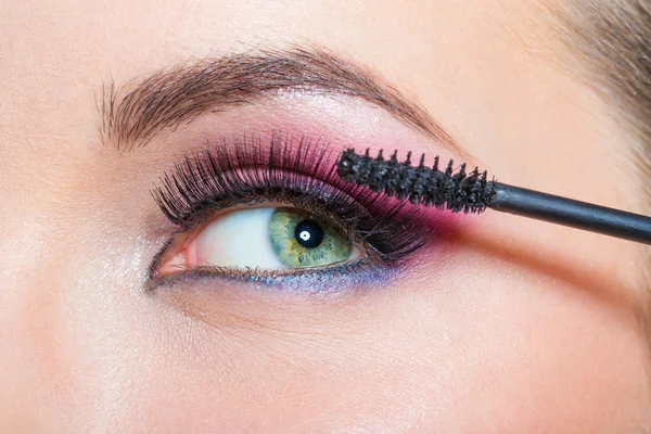 Nahaufnahme weiblicher Augen und Pinsel unter Anwendung von Wimperntusche — Stockfoto