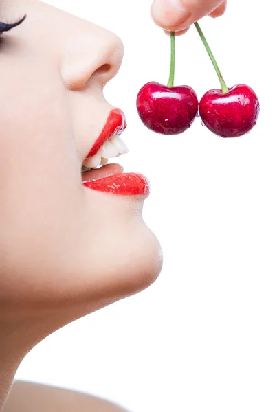 Close up of young girl with red lips eating two berries Stock Picture