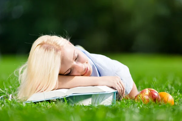 Κουρασμένος κορίτσι κοιμάται στα βιβλία που βρίσκεται στο γρασίδι — Φωτογραφία Αρχείου
