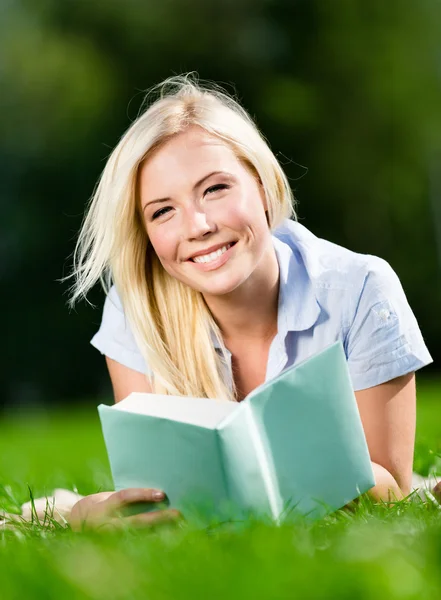 Молодая женщина лежит на траве и читает книгу — стоковое фото