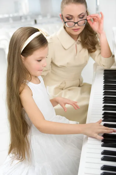 Handledare undervisar lilla flickan att spela piano — Stockfoto