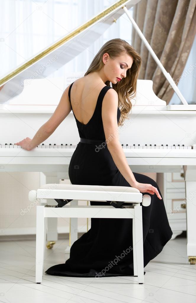 Back view of woman sitting and playing piano