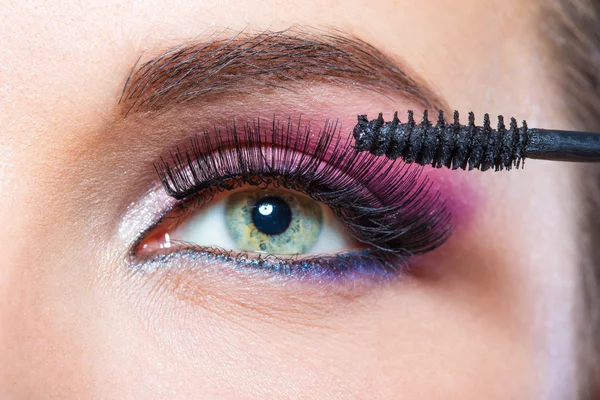 Close up shot of female eye and brush applying mascara — Stock Photo, Image