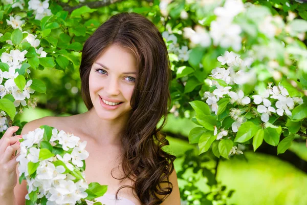 Beautiful woman near the flowered tree — Stock Photo, Image
