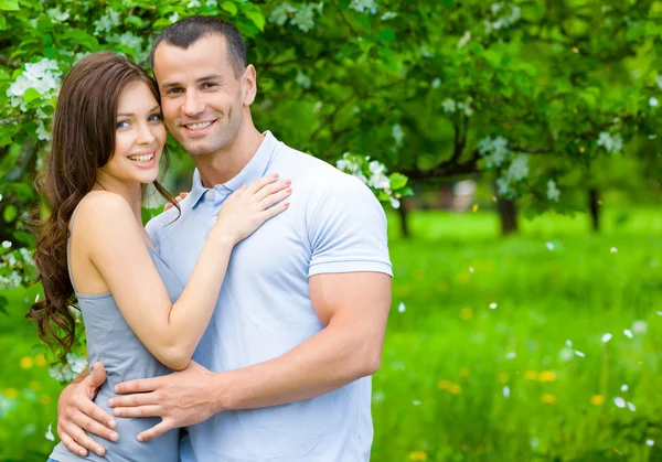 年轻夫妇拥抱附近花树 — 图库照片