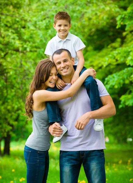 Glad familj på tre. pappa håller son på axlar — Stockfoto