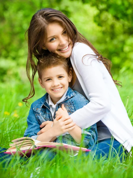 Mum and son with book in green park — Stock Photo, Image