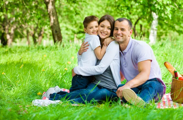 Dreiköpfige Familie picknickt im Park — Stockfoto
