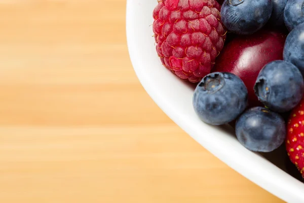 Close up view of par of plate full of berries on table — Stock Photo, Image
