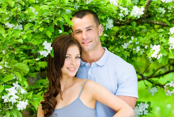Hübsches Paar umarmt sich in der Nähe eines blühenden Baumes — Stockfoto
