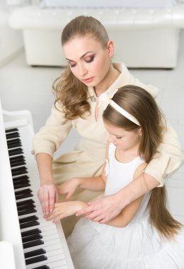 müzik öğretmeni küçük kız piyano çalmayı öğretir.