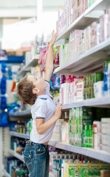Pequeño niño elige cosméticos en el mercado — Foto de Stock
