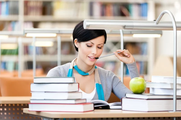 Smiley woman reads sitting at the desk — Stock Photo, Image