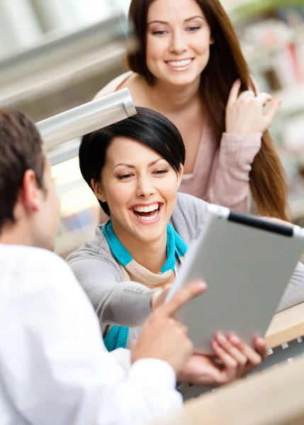 Man at the library shows pad to two women — Stock Photo, Image