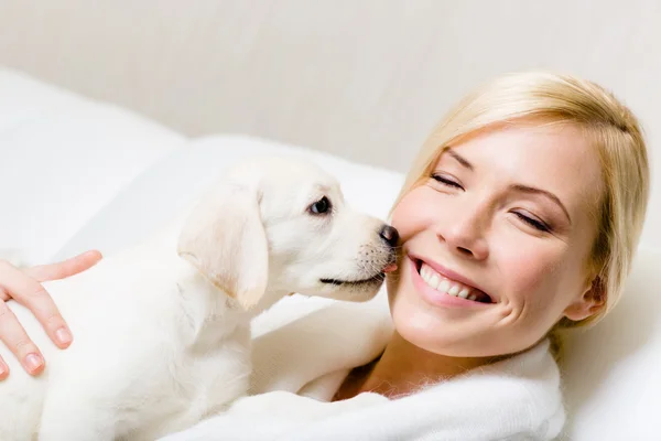Puppy of labrador licking the face of woman — Stock Photo, Image