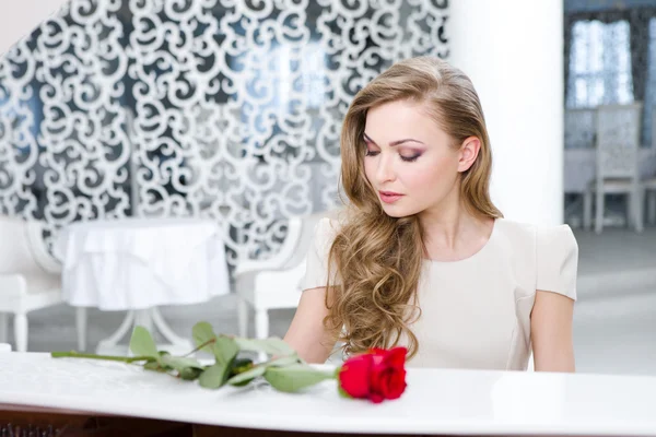 Portrait de femme avec rose rouge jouant du piano — Photo