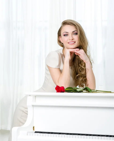 Portrait of woman standing near the piano and propping head — Stock Photo, Image