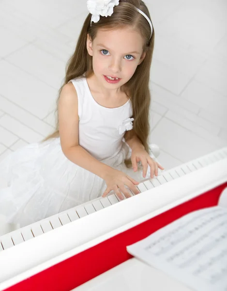 Porträtt av flicka i vit klänning spela piano — Stockfoto