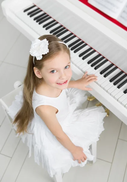 Ovansida av lite musiker i vit klänning spela piano — Stockfoto