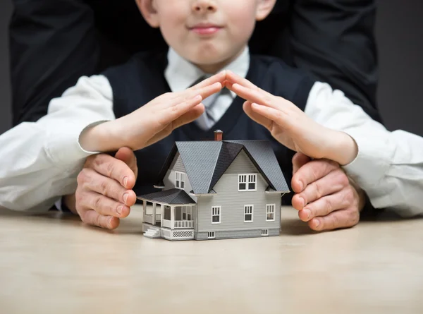 Little boy puts hands over house model — Stock Photo, Image