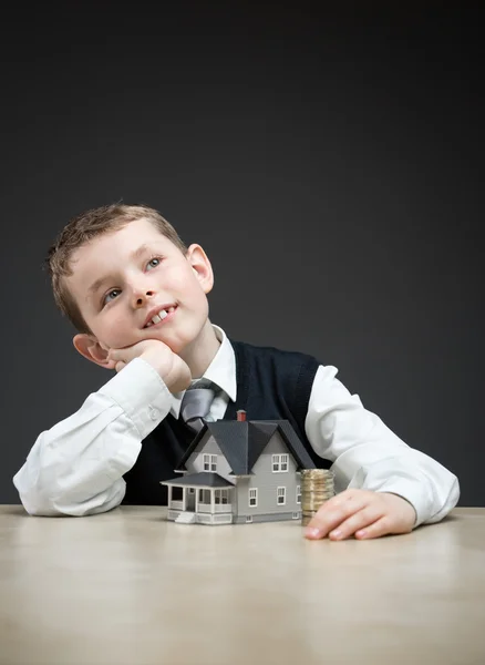 Niño pensativo con modelo de casa — Foto de Stock