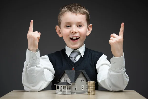 Kleiner Junge mit Hausmodell und Stapel Münzen — Stockfoto