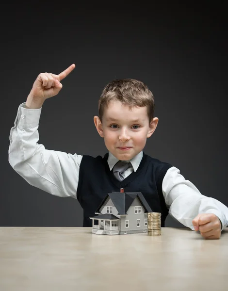 Boy with home model and pile of coins — Stock Photo, Image