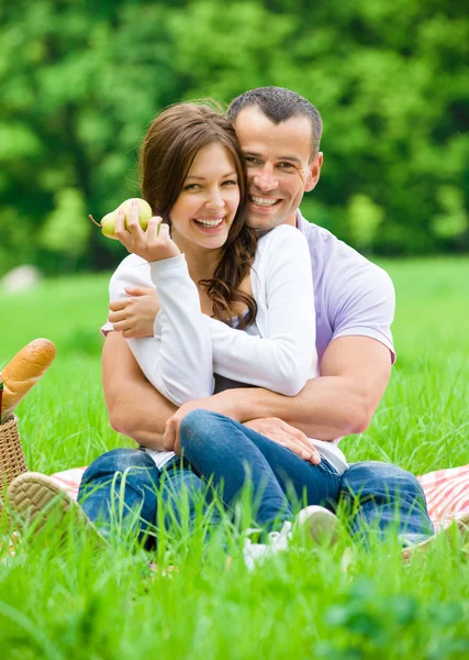 Man knuffels vrouw zittend op het gras in park — Stockfoto