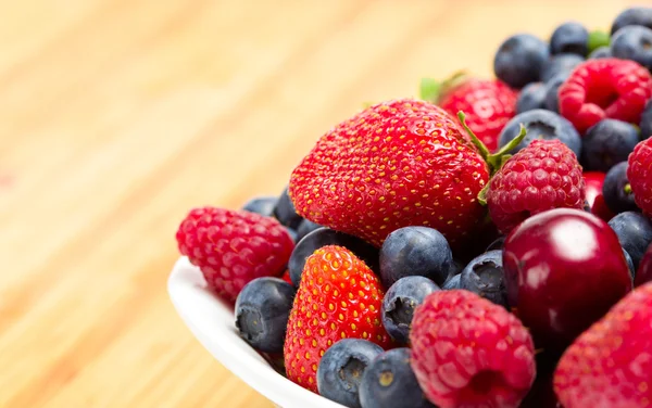 Nahaufnahme eines Tellers voller Beeren auf dem Tisch — Stockfoto