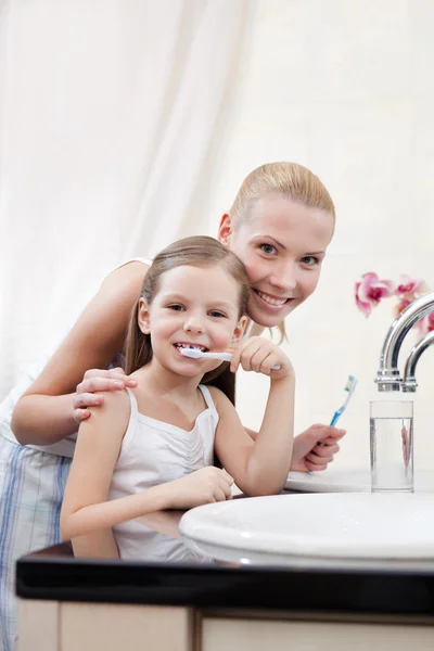 Küçük kızın dişleri annesiyle temizler. — Stok fotoğraf