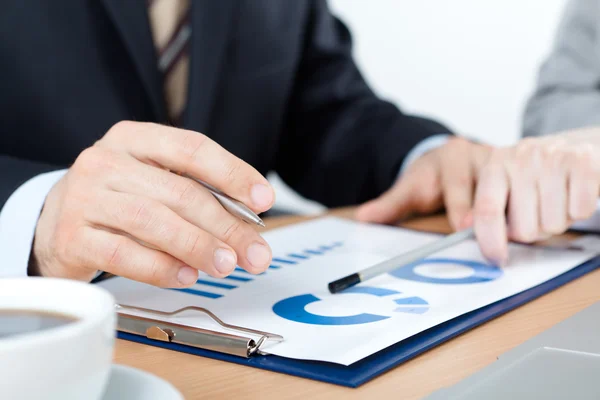 Hands of business people holding pen — Stock Photo, Image