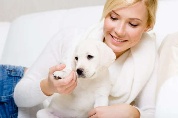 Beyaz köpek yavrusu ile kanepede kadındır — Stok fotoğraf