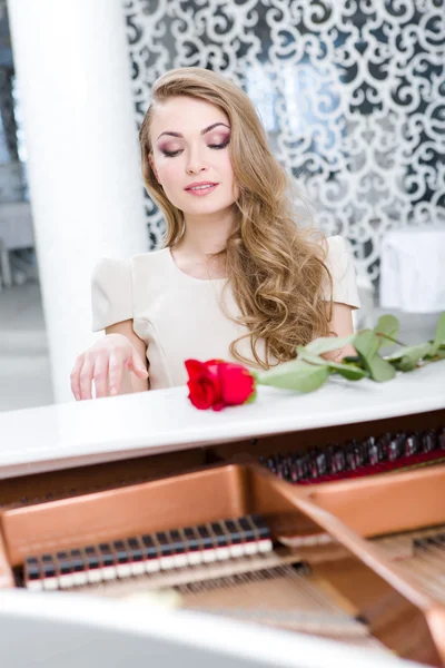 Portrait of woman with claret rose playing piano — Stock Photo, Image