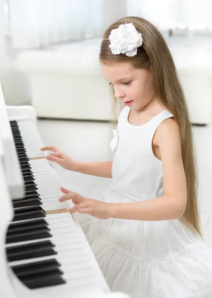 Portrait of little girl in white dress playing piano — Stock Photo, Image