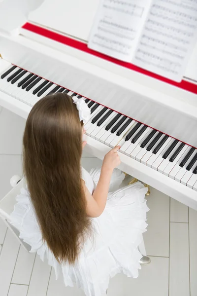 Bovenaanzicht van klein kind in witte jurk pianospelen — Stockfoto