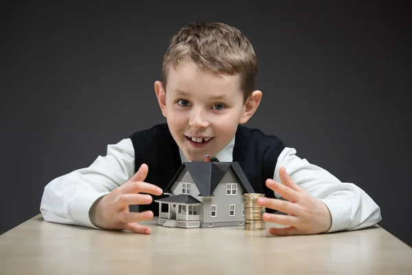 Kleine jongen weg te nemen huis model en stapel van munten — Stockfoto