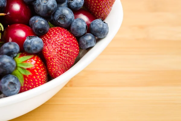 Close-up of par of plate full of berries on table — Stock Photo, Image