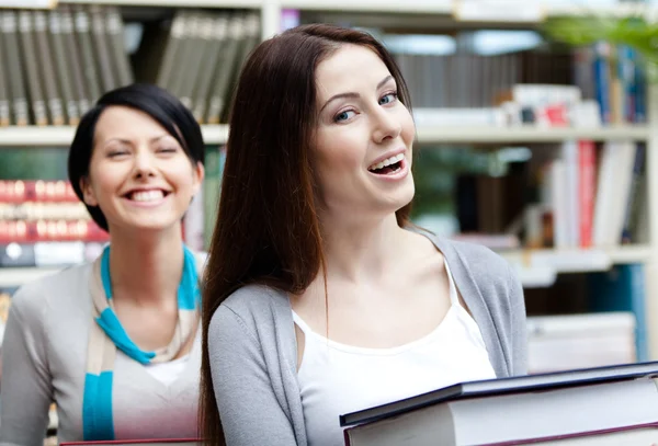 Two laughing girlfriends carry books — Stock Photo, Image