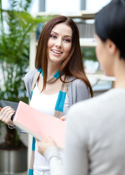 Female undergraduate offers a book to her friend — Stock Photo, Image