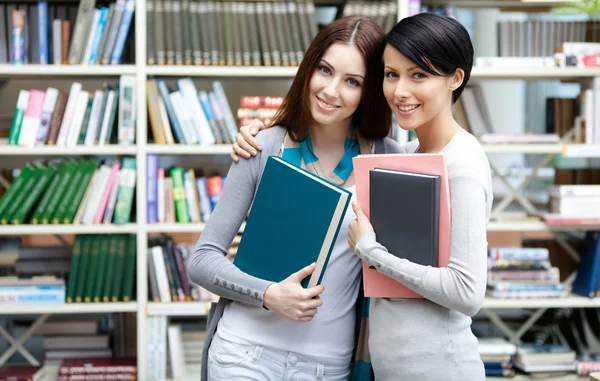 Twee vriendinnen hug op de bibliotheek — Stockfoto