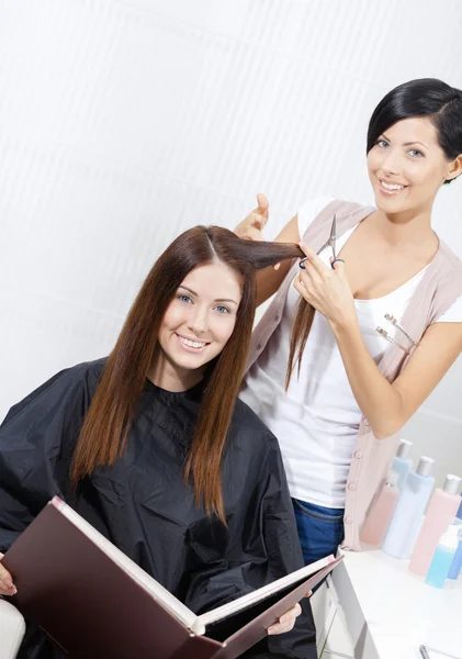 Косметик стрижет волосы женщины в косметологе — стоковое фото