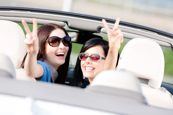 Två tjejer sitter i bilen och gestikulerande seger tecken — Stockfoto