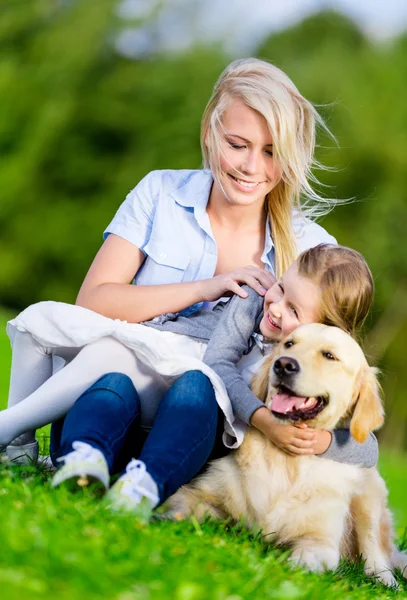 Mother and daughter with retriever are on the grass — Stock Photo, Image