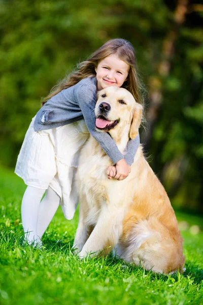Menina Pequena Menina abraça golden retriever no parque — Fotografia de Stock