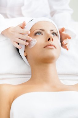 Terapistin elleri kadın yüzüne krem sürsün.