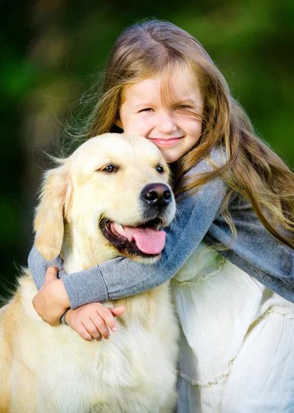 Little girl embraces golden retriever in the park — Stock Photo, Image
